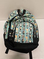 Front view of Tracker owl print backpack showing pattern, zip compartments, keychain