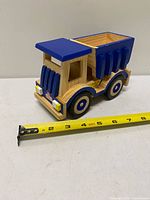 Full view of wooden dump truck beside tape measure showing length