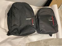 Front view of two Lenovo backpacks showing logos and red zipper accents