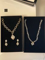 Two boxed Heidi Daus necklace sets side by side