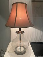 Full view of lamp showing glass body, metal accents, shade and cord