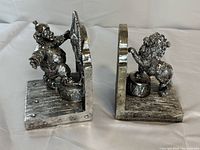 Both bookends side by side showing clown and lion figures, metallic silver finish