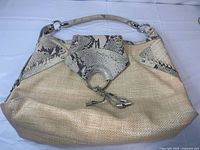 Front view of raffia handbag showing snakeskin panels and ring hardware