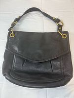 Front view of black leather Fossil shoulder bag showing flap and strap.
