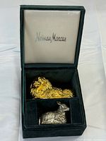 Open box showing gold lion and silver lamb shakers inside, Neiman Marcus logo on lid