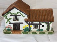 Front view of ceramic mission showing facade, doors, windows, vines, flowers, roof, power cord visible