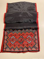 Full view of black silk scarf showing patterned end and plain section