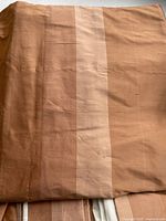 Folded striped silk valance showing muted cinnamon tones and stripe pattern