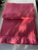 Folded hot pink wool blanket showing satin bound edge