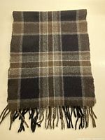 Full view of scarf folded showing plaid pattern and fringe