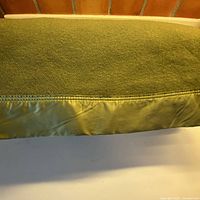 Close-up of satin bound edge on green wool blanket