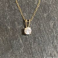 Close-up of cubic zirconia pendant, gold setting and chain links visible