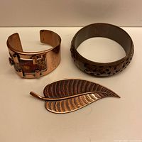 Overall view of cuff bracelet, leaf brooch, and cut-out bangle.