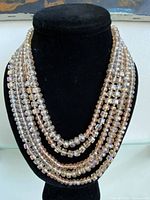 Full view of five-strand iridescent bead necklace on display bust