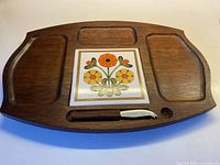 Full view of wood cheese board with floral tile and knife in slot