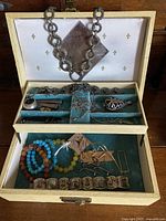 Jewellery box open showing assorted jewellery in tray and lower compartment