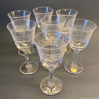 Front view of all seven etched liqueur glasses showing overall condition and labels