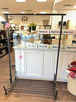 Full view of black metal garment rack showing top hanging bar, sides, and slatted bottom shelf