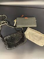 Group shot of all three items: black beaded purse, metal mesh clutch, Fossil wallet
