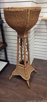 Full view of wicker plant stand showing height and design