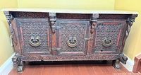 Front view of carved wooden sideboard showing all three doors and hardware