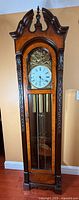 Full view of longcase clock showing wood case, glazed door, pendulum