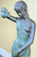 Front view of bronze female figure sculpture showing pose and pitcher