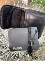 Bushnell rangefinder front profile with cord and case visible