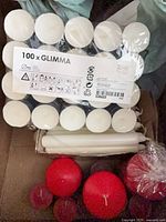 Sealed 100-count GLIMMA tealights, white tapers, red pillar candles