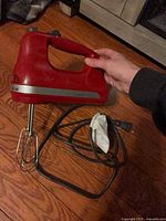 Full view of red KitchenAid hand mixer with beaters and cord