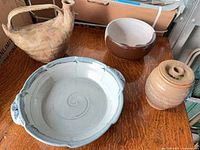 Four handmade pottery pieces on table: pitcher, serving dish, bowl, jar