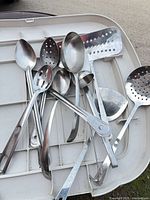 Pile of mixed stainless steel utensils on tray