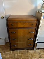 Front view of tall chest showing four drawers and decorative pulls