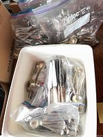 Large plastic bin and bags filled with assorted silver-plate flatware