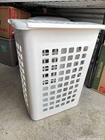 Three-quarter side view of white Sterilite hamper showing ventilation holes and attached lid