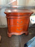 Front view showing two drawers, serpentine shape, cherry finish, metal bail pulls
