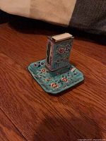 Holder seated on tray showing floral enamel sides and turquoise ground