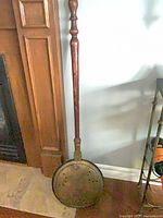 Full view of bed warmer leaning against wall