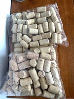 Two sealed bags of unused corks on wooden surface