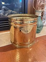 Front view of hammered brass planter showing ribbed bands