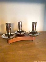Front view of three-light candle holder on wooden base