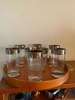 Set of six silver band tumblers on teak tray