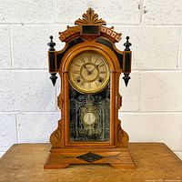 Full view of wooden Ansonia mantel clock on table