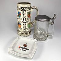 Front view of three items: ashtray, ceramic stein, glass stein