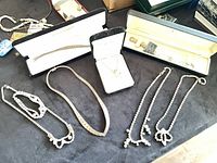 Overview of nine assorted jewelry pieces on table with three boxed items and several rhinestone necklaces