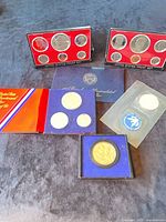 Two proof sets, commemorative round and additional packaging visible