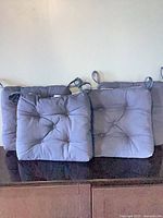 Front view of all four navy tufted cushions standing upright showing overall design and quantity