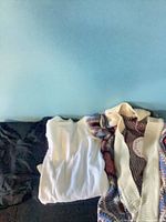 Three tops laid out: black, white, multicolour cardigan