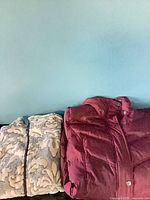 Burgundy puffer jacket and cream/grey fleece jacket side by side