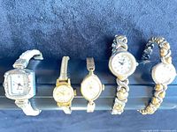 Front view of all five watches side by side on display rod